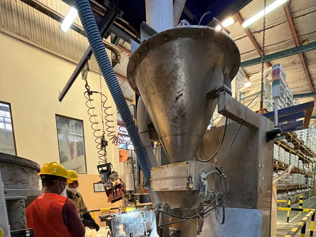 Bagging machine dengan hopper penakar dan spout pengisi karung di gudang pengemasan